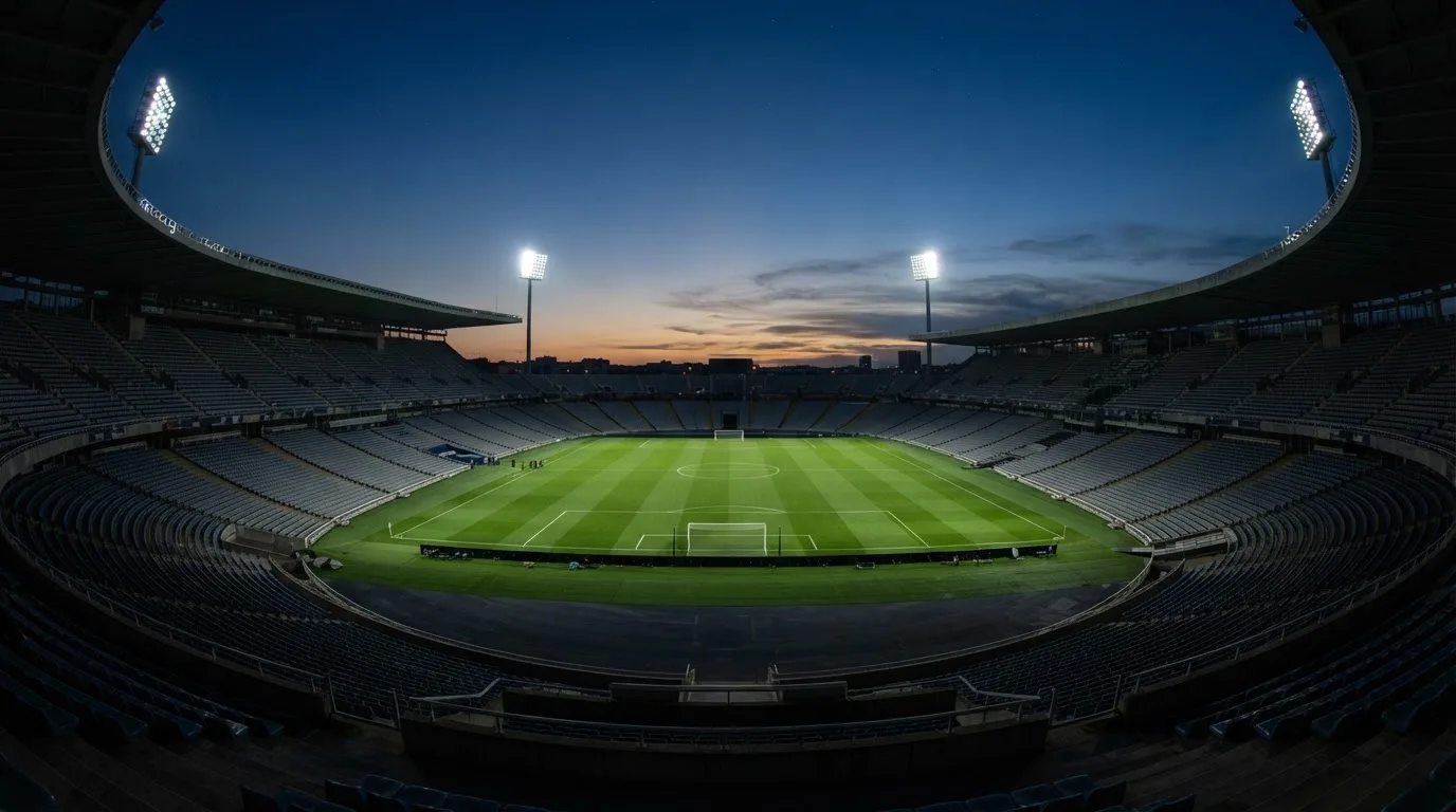 An empty football stadium with floodlight masts at dusk