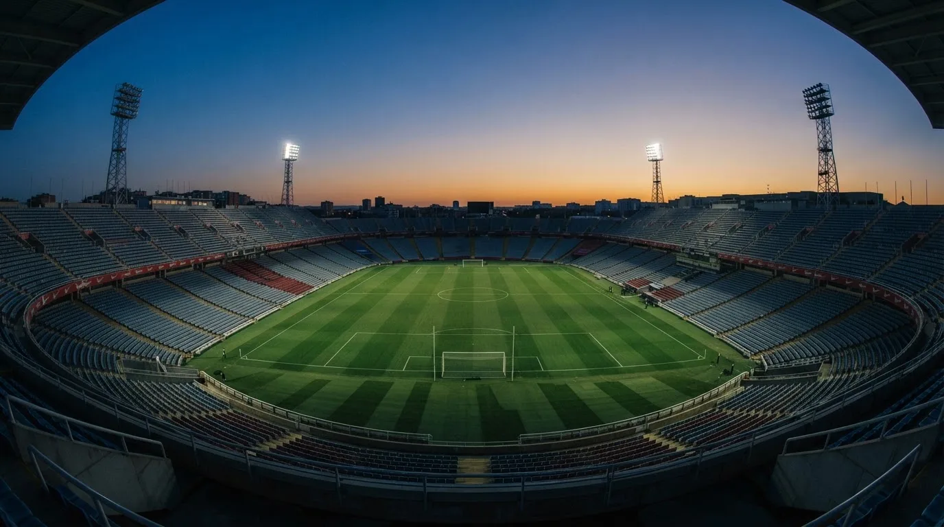 An empty football stadium with floodlight masts at dusk