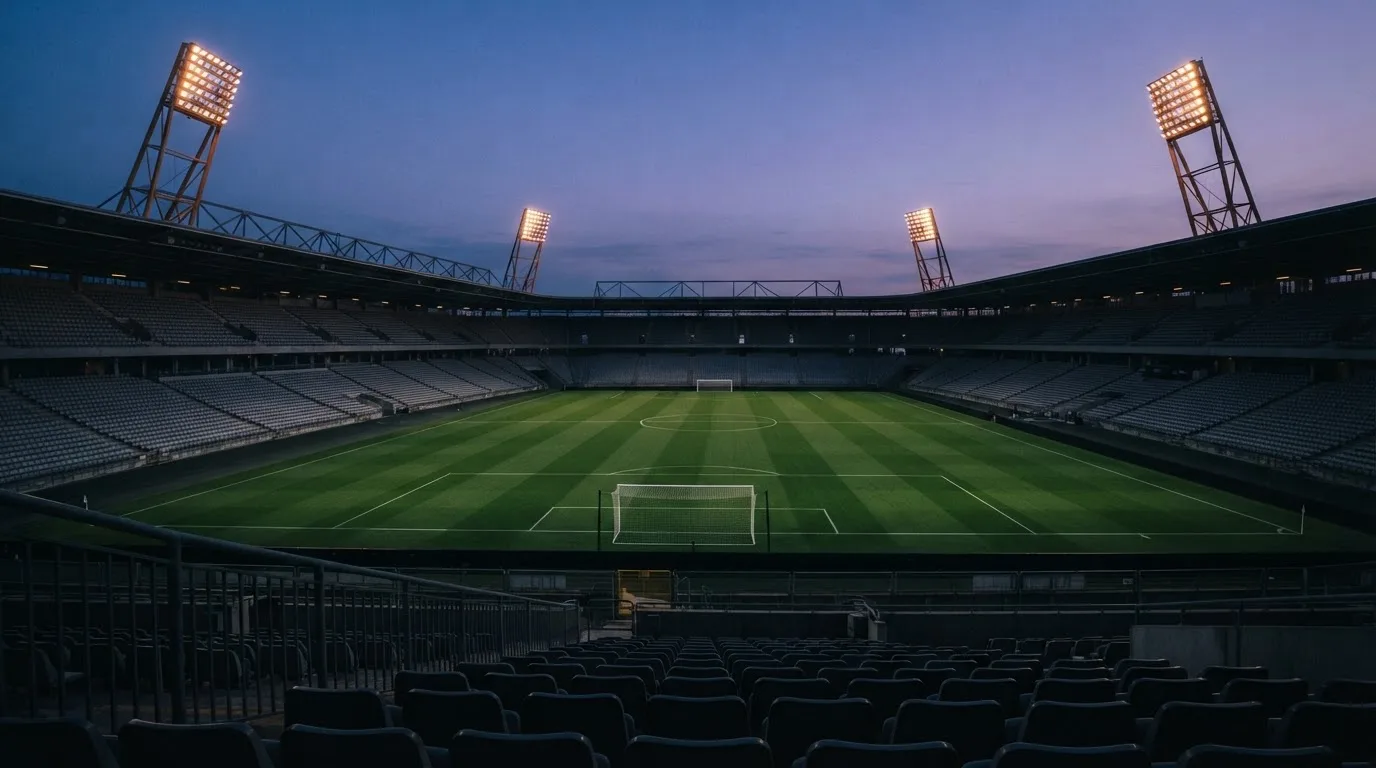 An empty football stadium with floodlight masts at dusk