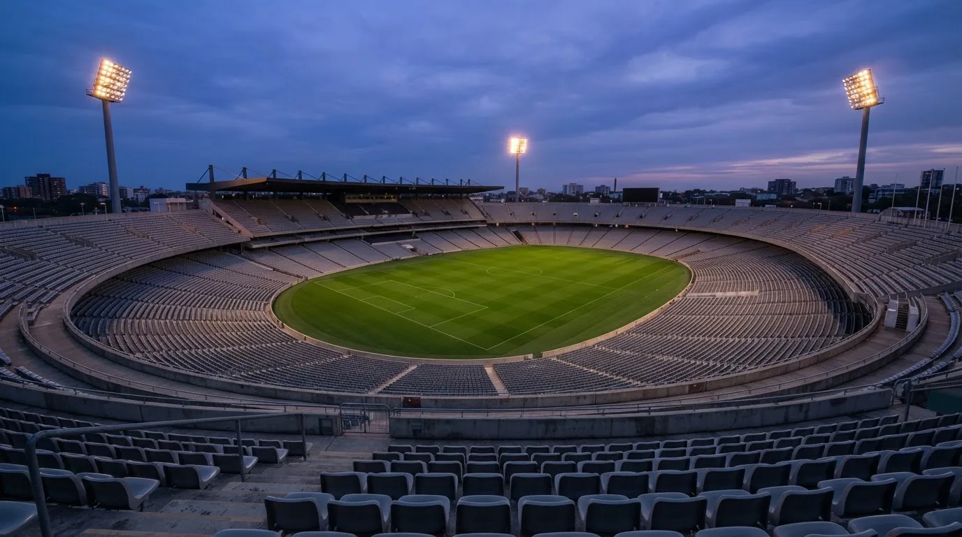An empty football stadium with floodlight masts at dusk