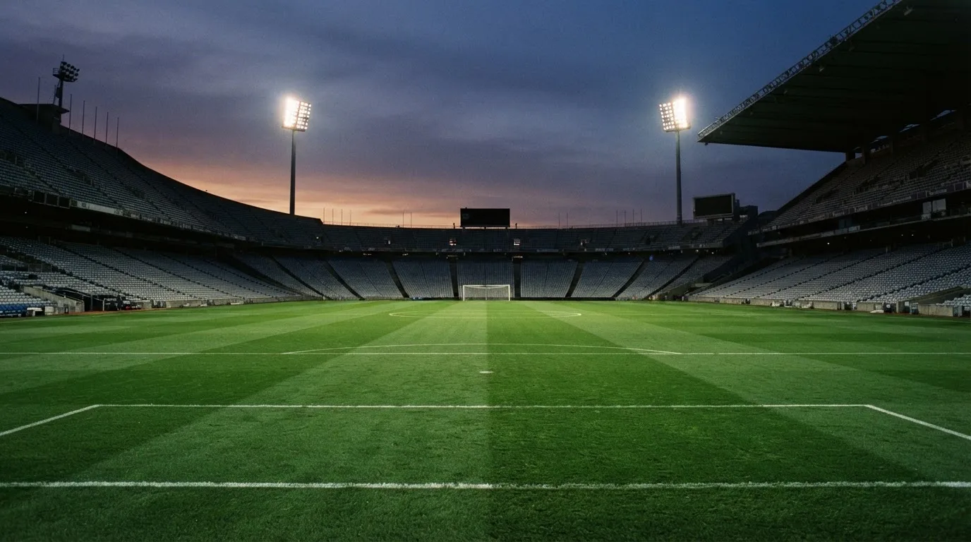 An empty football stadium with floodlight masts at dusk