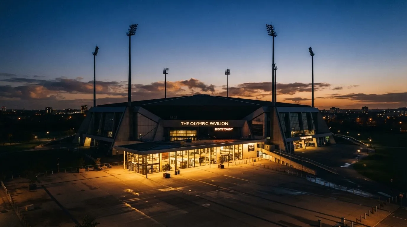 An empty football stadium with floodlight masts at dusk