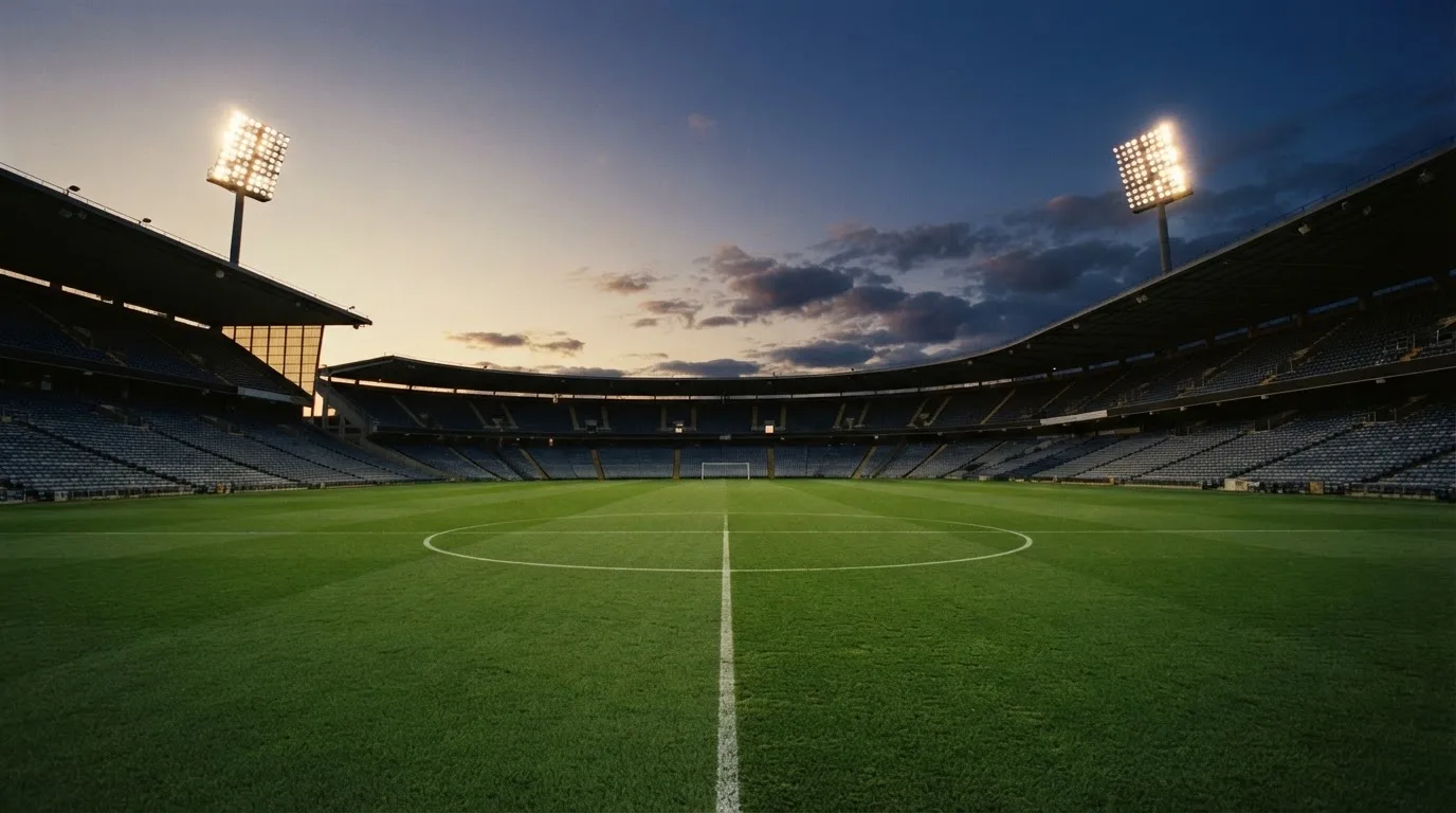 An empty football stadium with floodlight masts at dusk