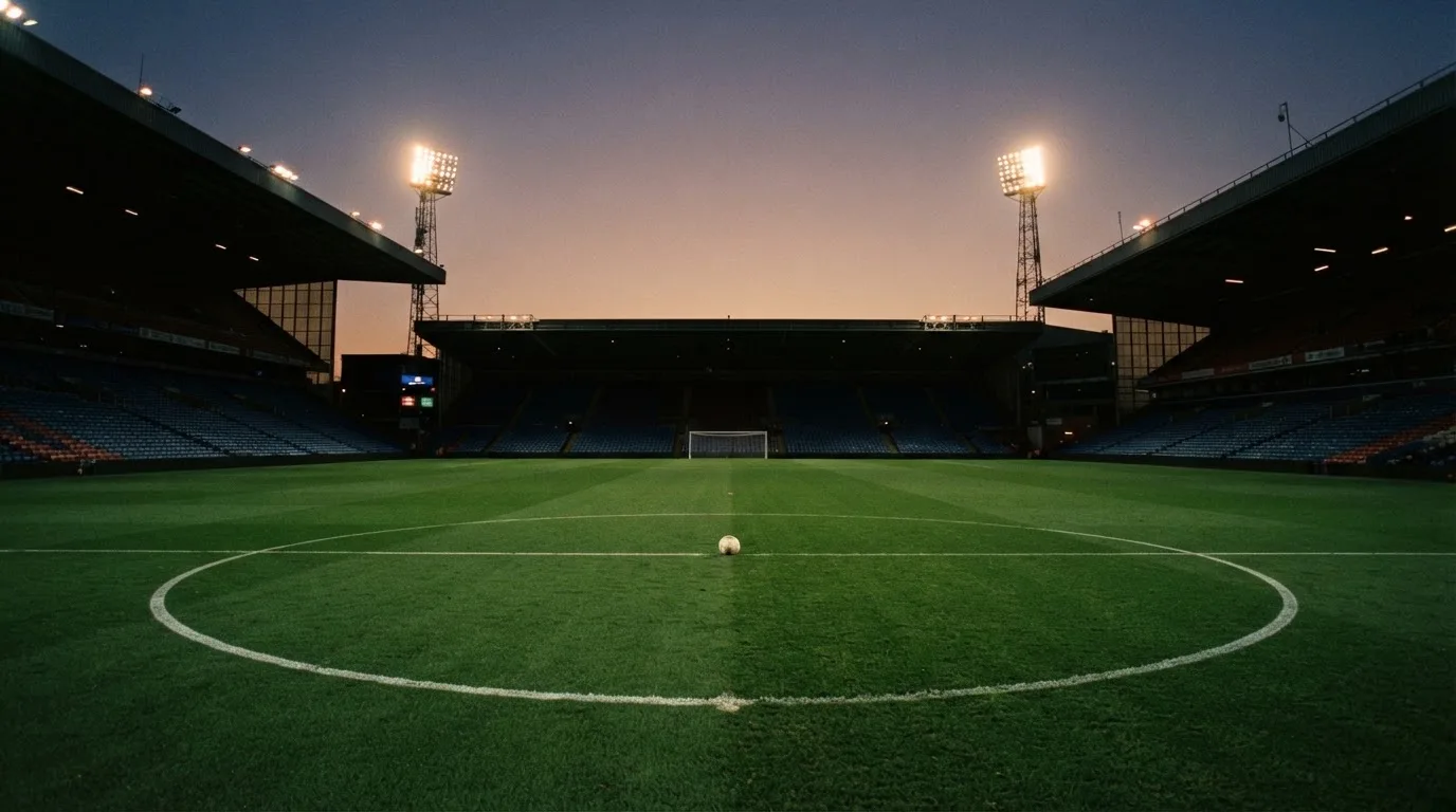 An empty football stadium with floodlight masts at dusk