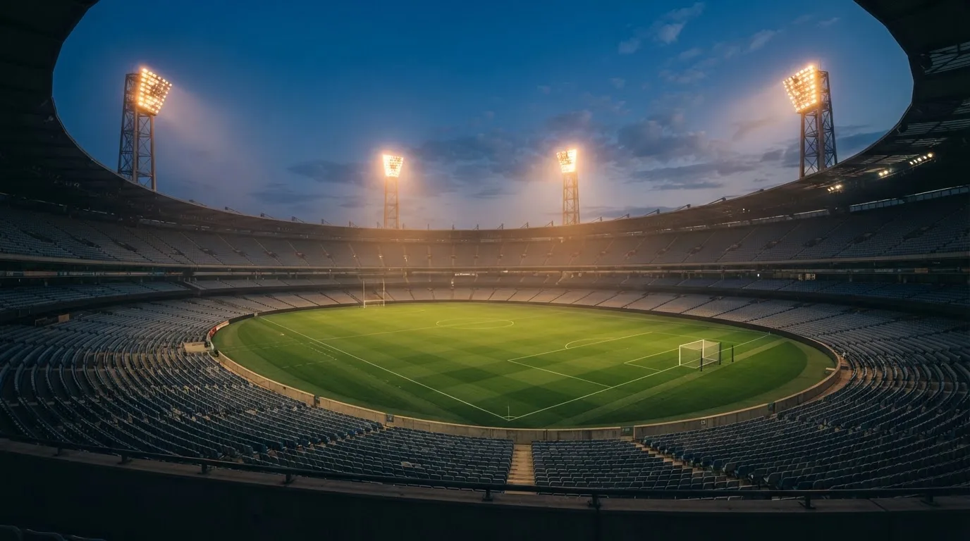 An empty football stadium with floodlight masts at dusk