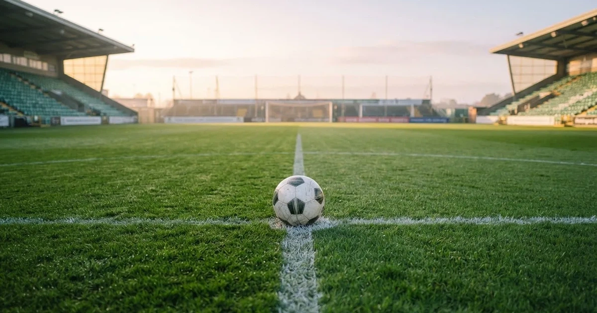A ball on the centre spot of a grass pitch in morning light