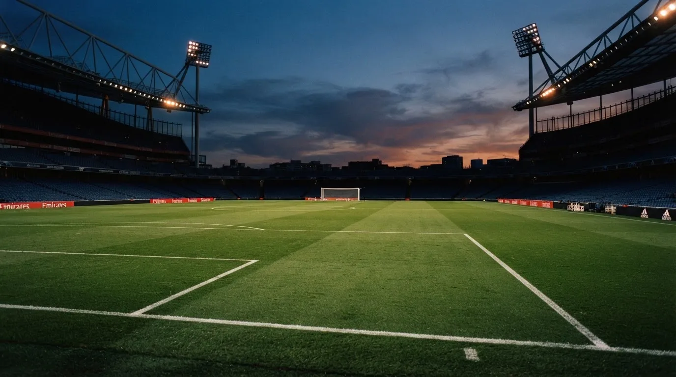 An empty football stadium with floodlight masts at dusk